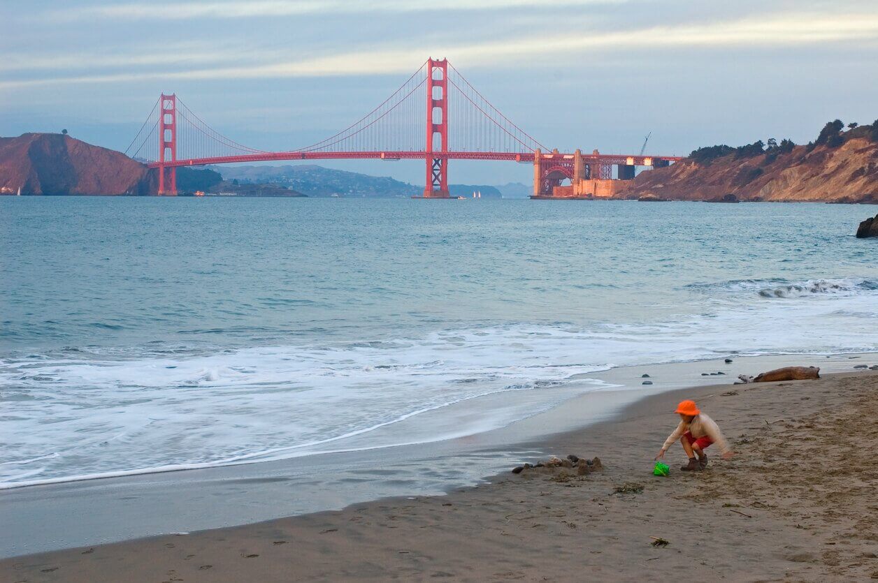 Fille jouant sur la plage Golden Gate - Où partir seule avec un enfant ? Les 12 meilleures destinations pour les mamans solos et leur(s) enfant(s) !